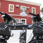 Biciclette elettriche Vaimoo parcheggiate davanti alla stazione di Altamura, edificio rosso sullo sfondo.