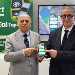 Due uomini mostrano orgogliosi un’app per il trasporto pubblico, alla presentazione della tecnologia per viaggi smart.