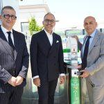 Tre uomini sorridenti posano vicino a un terminale di pagamento contactless per il trasporto pubblico.